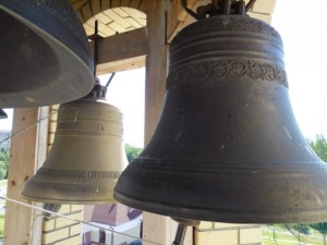 Фото на колокольне храма, несколько колоколов от которых тянутся толстые веревки